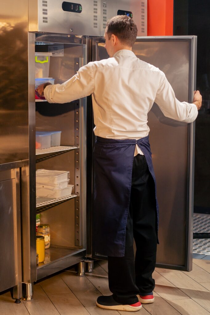 professional kitchen chef looks into the fridge and chooses ingredients for cooking food concept